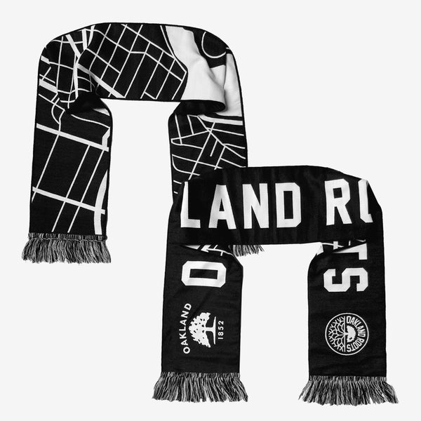 Black & white two-sided woven scarf folded in U shape to show both sides and ends with “OAKLAND ROOTS”  wordmark, circle logo, Oakland 1852 Flag logo, and graphic map of Oakland.