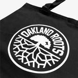 Close-up of black reusable shopping tote with large white Oakland Roots logo crest.