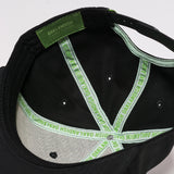 The underside of a black snapback cap with an Oaklandish tag and taping.