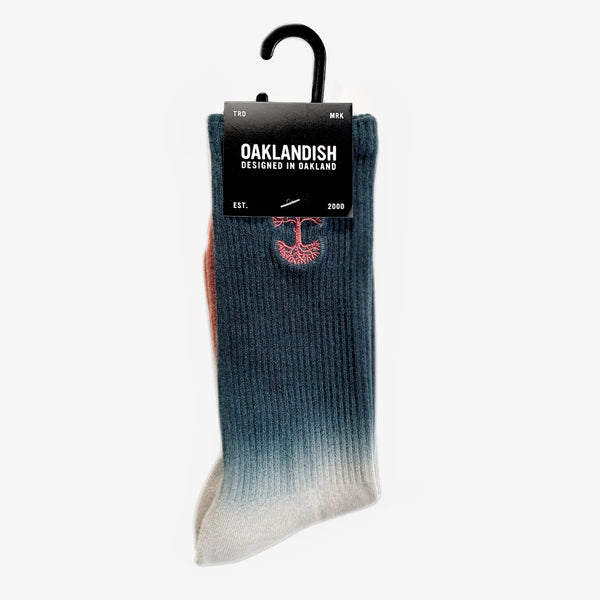High-cut dip-dyed crew socks (navy, grey and pink) folded into an Oaklandish retail package.