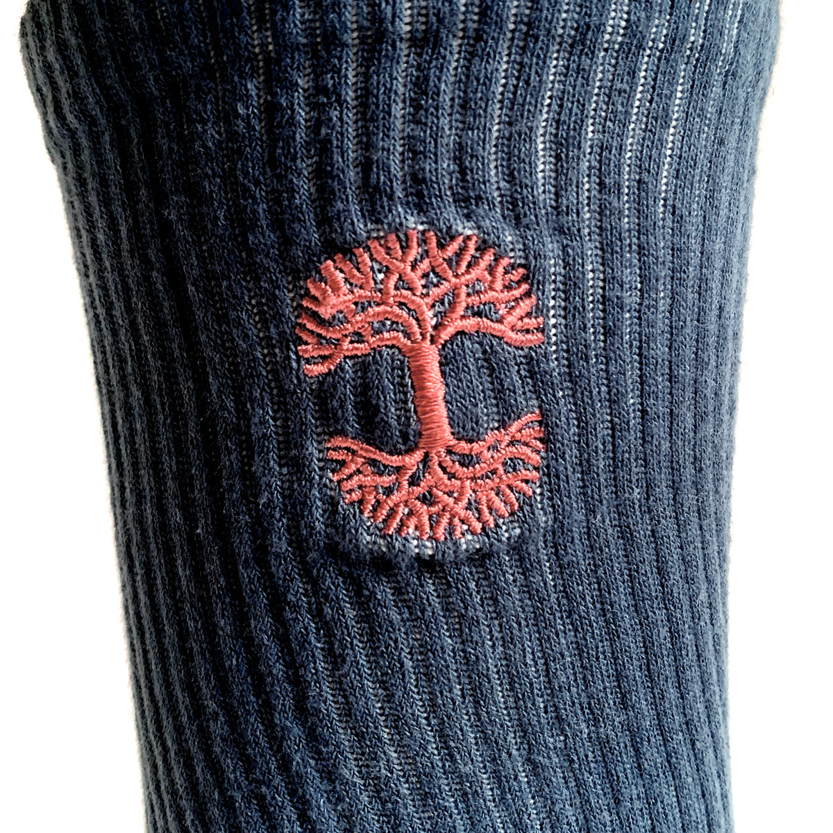 Close up of embroidered Oaklandish logo at the top of dip-dyed (navy, grey and pink) men’s crew socks.