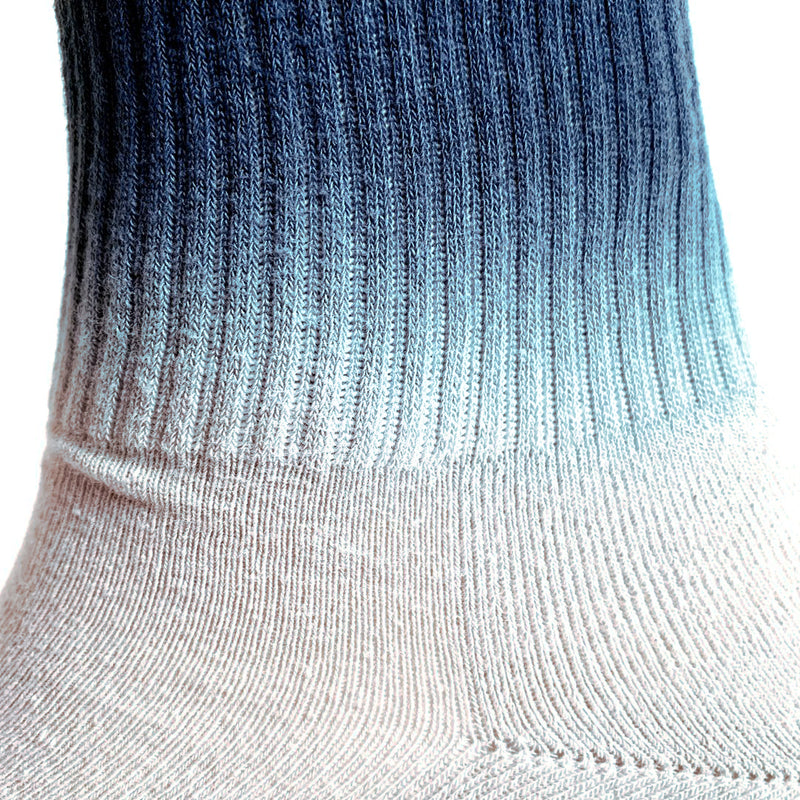 Close up of the grey and navy colors blending at the ankle of high-cut dip-dyed crew sock.