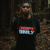A woman standing in a forest in a black women's t-shirt with a large red and white DOPE ONLY wordmark logo on the chest.