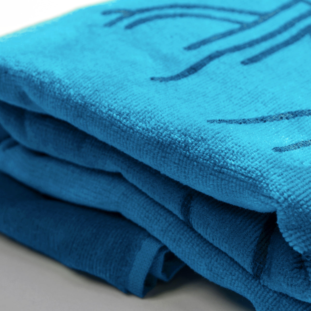 Detailed close up of Oaklandish logo outlines on a folded oversized super plush aqua blue beach towel.