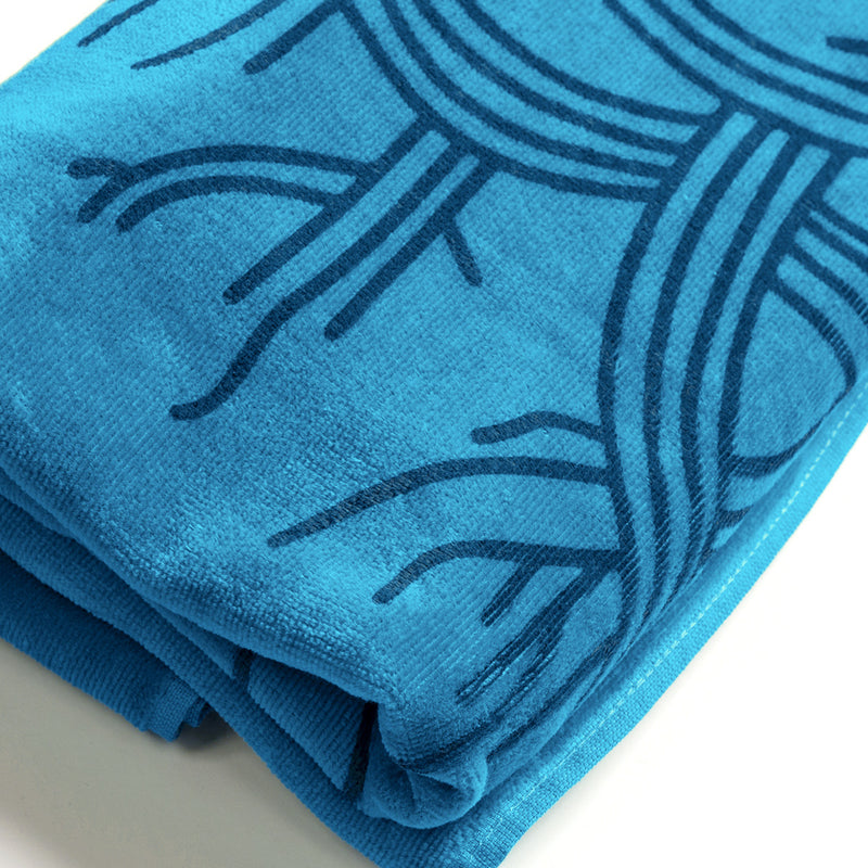 Close up of Oaklandish logo outlines on a folded oversized super plush aqua blue beach towel.