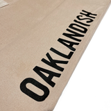 Close up of Oaklandish wordmark on brown natural denim extra large tote bag. 