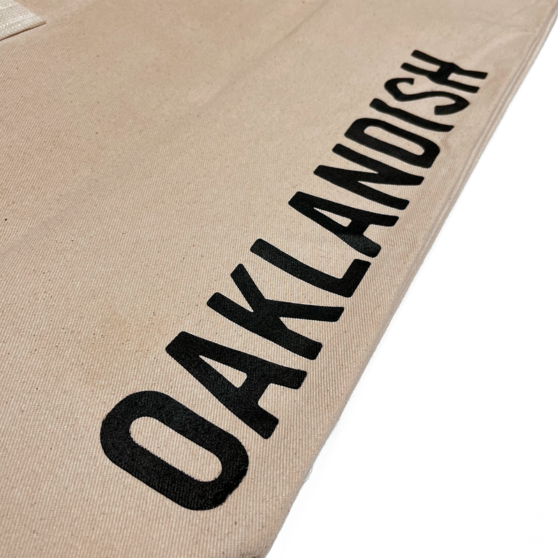 Close up of Oaklandish wordmark on brown natural denim extra large tote bag. 