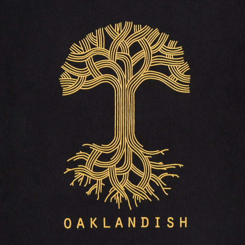 Close-up of gold Oaklandish tree logo and wordmark on the chest of a women’s cut black long-sleeve t-shirt.