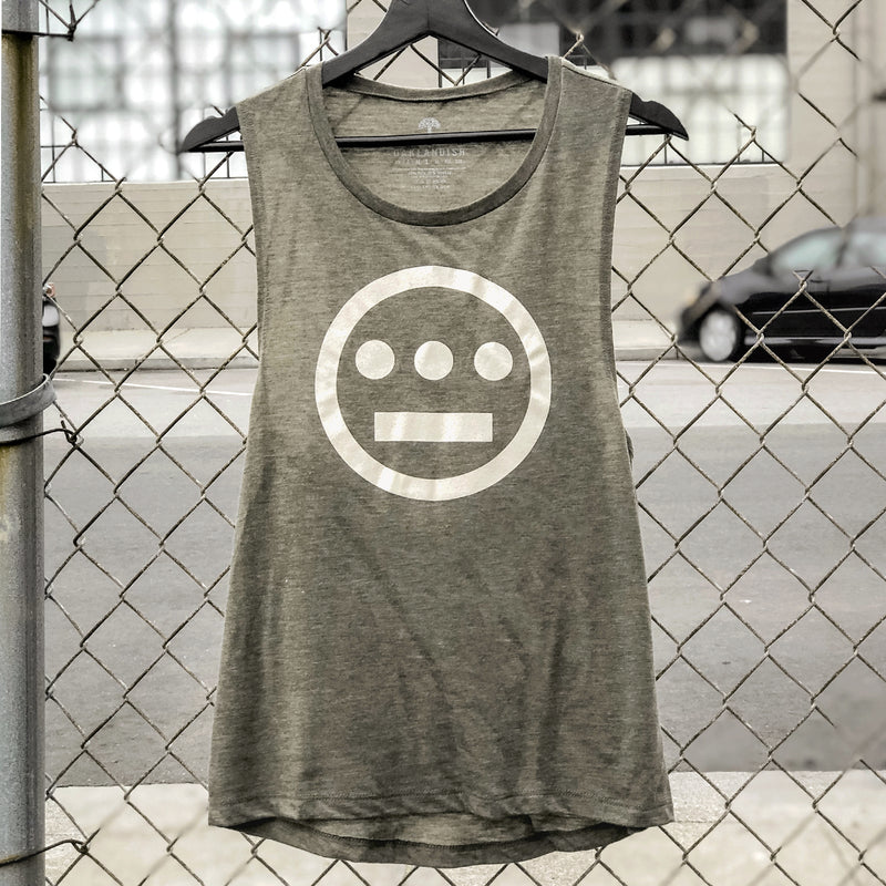 Women's olive green tank top with creme Hiero Hip Hop Crew Classic Logo on chest hanging outdoors on a chain-link fence.