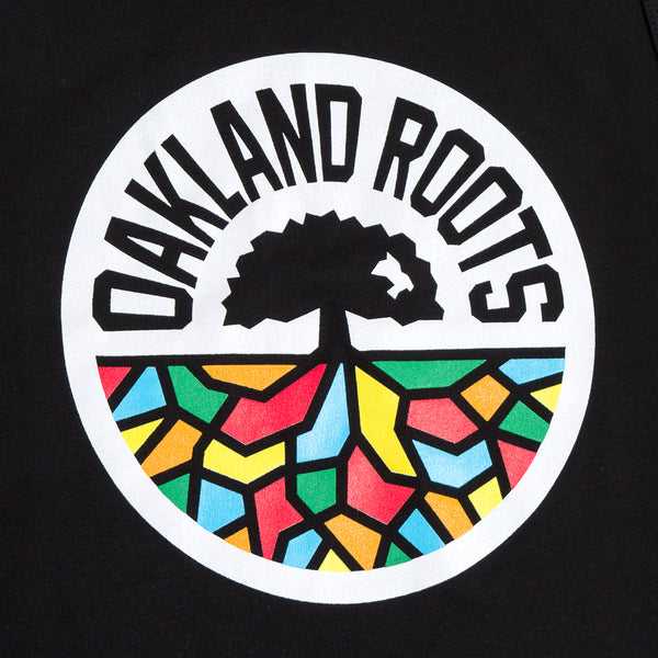 Close-up of full-color Oakland Roots circle logo on the chest of a women’s black tank top.