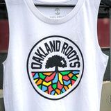 Close-up of women’s cut white tank top with full-color Oakland Roots circle logo on the chest hanging outside. 