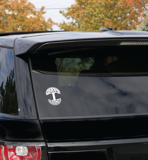 Large-sized white Oaklandish tree logo car window decal on the back window of a black SUV car. 