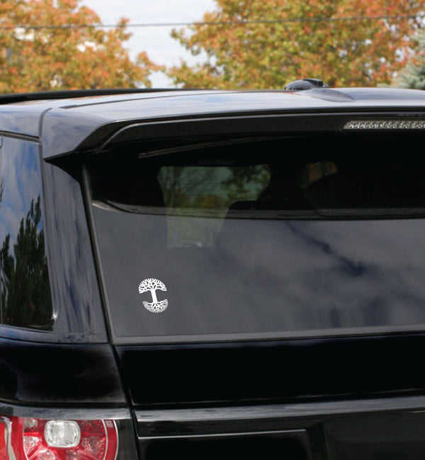 Medium-sized white Oaklandish tree logo car window decal on the back window of a black SUV car. 