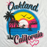 Close-up of pink, black, yellow, and blue Oakland California Wonderland graphic on the chest of a white tank top.