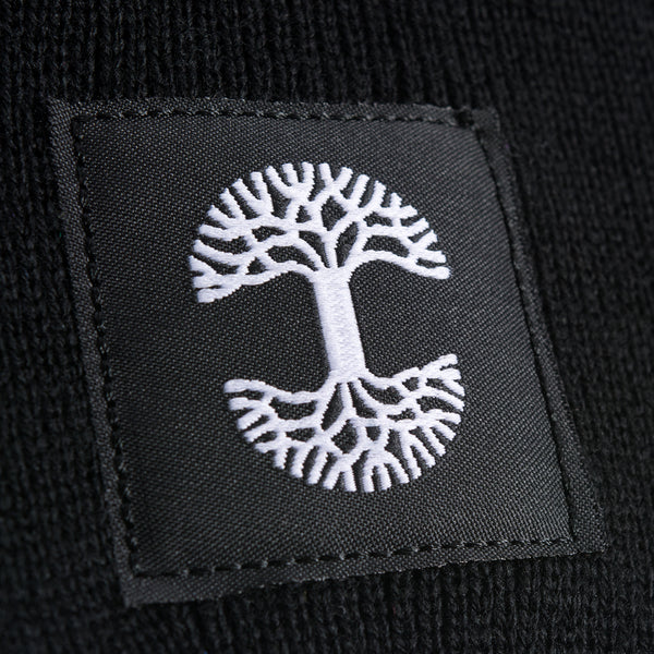 A close-up of the black and white Oaklandish logo tag on black woven beanie.