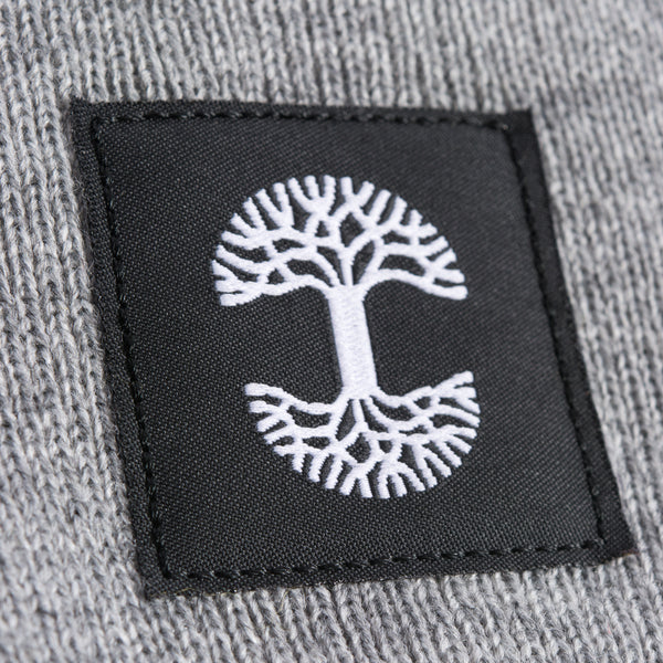 A close-up of the black and white Oaklandish logo tag on a grey woven beanie.