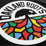 Close-up of a full color Oakland Roots logo crest on a black youth sized hoodie.